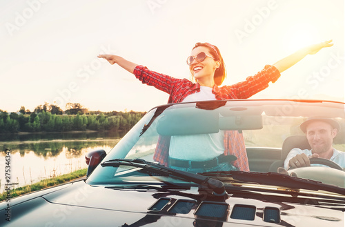 Happy couple in love go by cabriolet car in sunset time