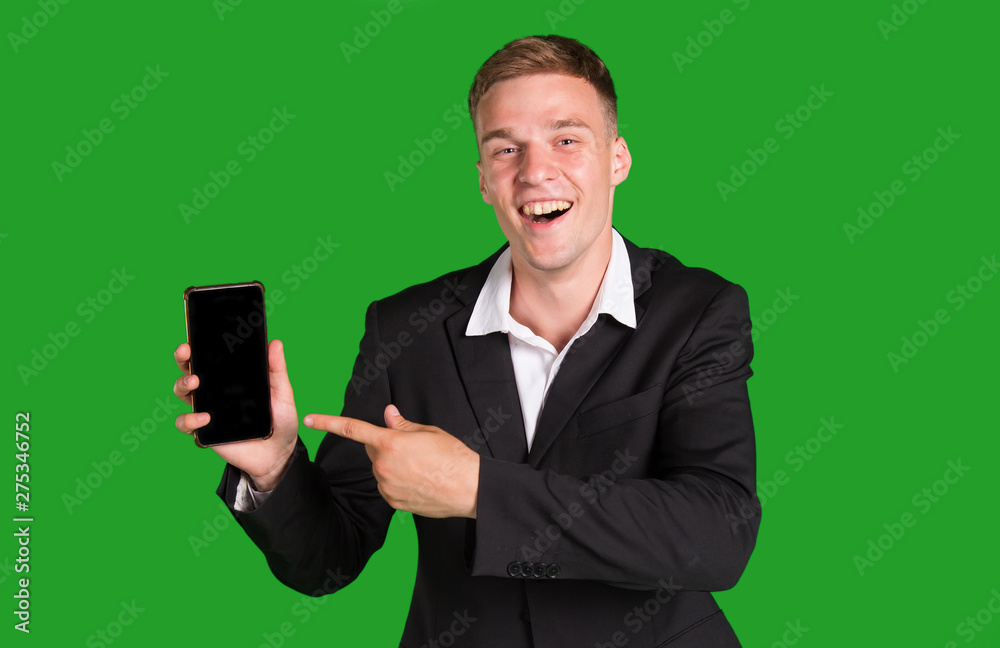 Happy man in suit shows a finger to his smartphone, isolated on green background. Get a win. Happy man in suit shows a finger to his smartphone, isolated on green background. Get a win.
