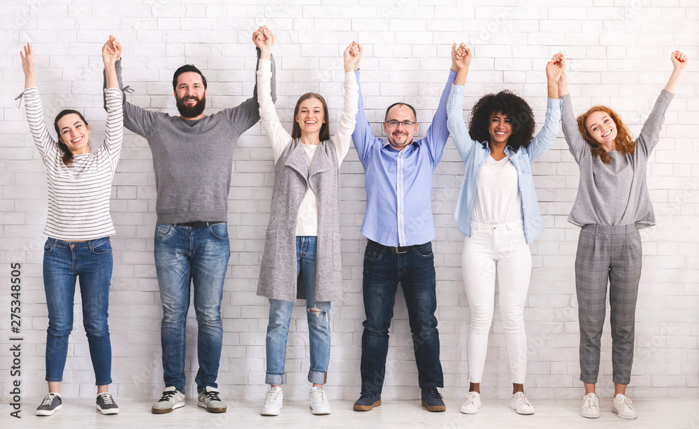 Group of successful friendly people raising connected hands