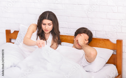 Fotografie Woman in bed looking under blanket, man with erectile dysfunction