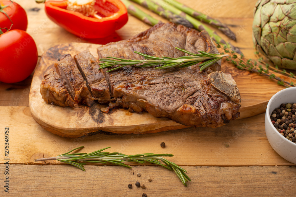 Marbled beef steak on a board with rosemary pepper, seasoning, and fresh vegetables on a wooden background, restaurant menu, gastronomy, tasty food. Restaurant service Marbled beef steak on a board with rosemary pepper, seasoning, and fresh vegetables on a wooden background, restaurant menu, gastronomy, tasty food. Restaurant service