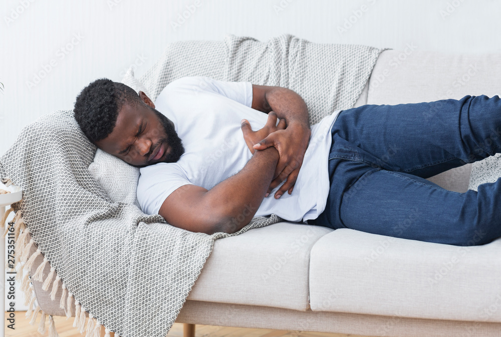 Obraz premium Desperate young african man hugging his belly