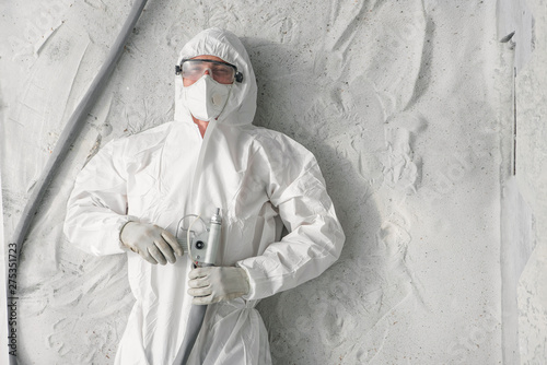 Foto A man in white protective uniform, respirator and plastic transparent glasses