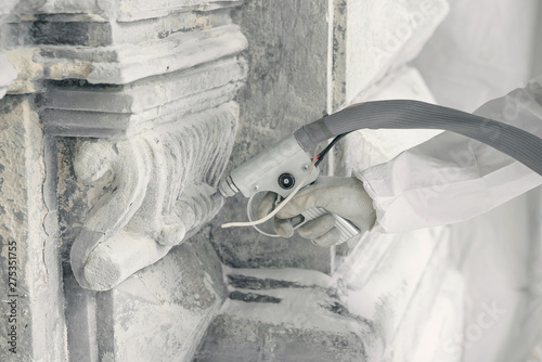 Hand of worker with the gun for serving a high-pressure sand jet. Restoration of historical buildind with stone carved decorative elements. photo