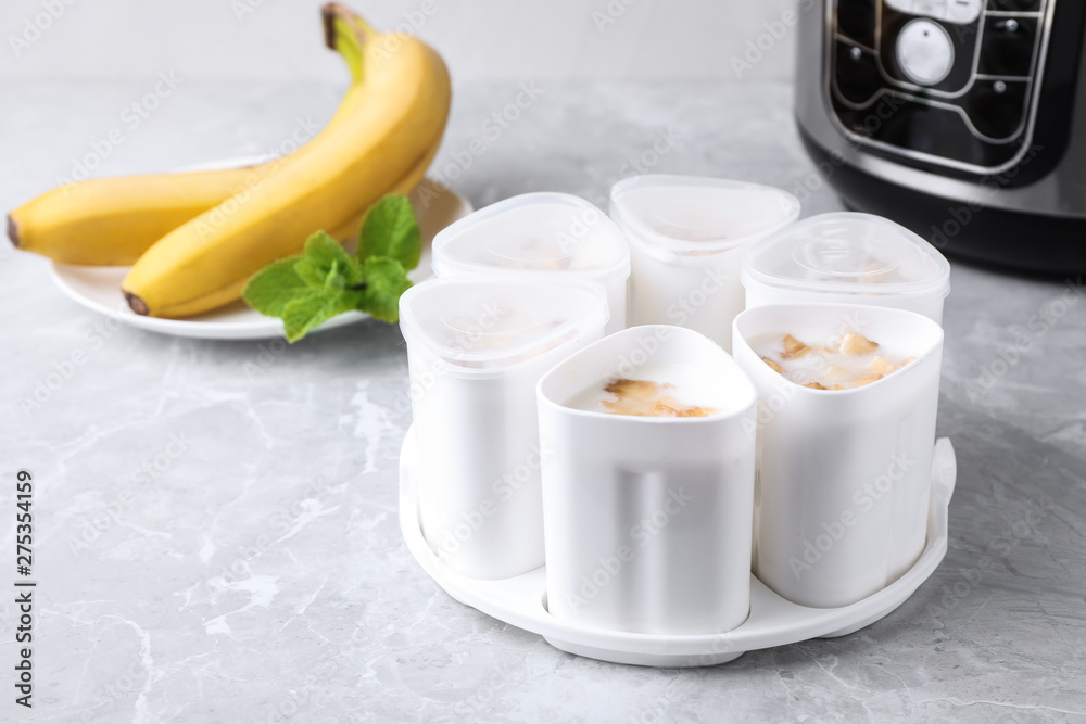 Cups of yogurt with bananas and multi cooker on table Cups of yogurt with bananas and multi cooker on table