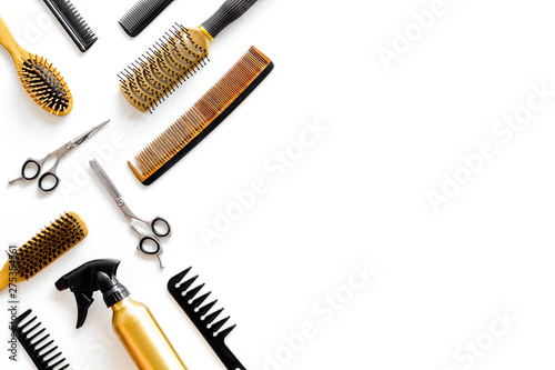 professional accessories of hairdresser with combs and spray on work desk white background top view copyspace