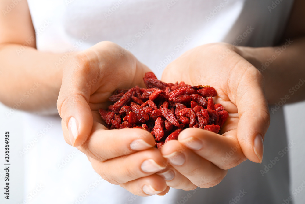 Woman holding red dried goji berries, closeup