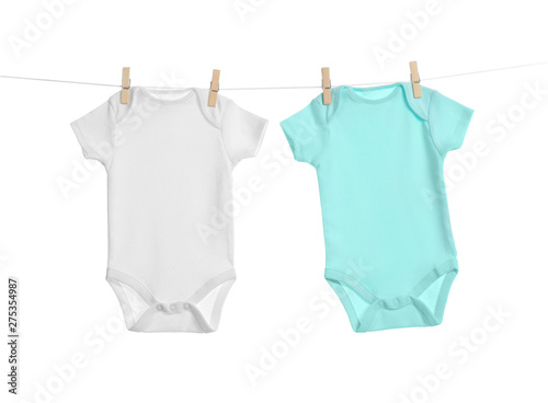 Colorful baby onesies hanging on clothes line against white background. Laundry day