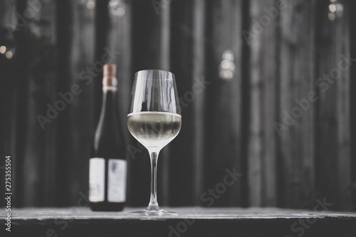 Image of white wine glass with white wine bottle and blurry background