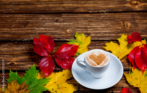 photo of cup of coffee and autumn leaves on the wonderful brown wooden background