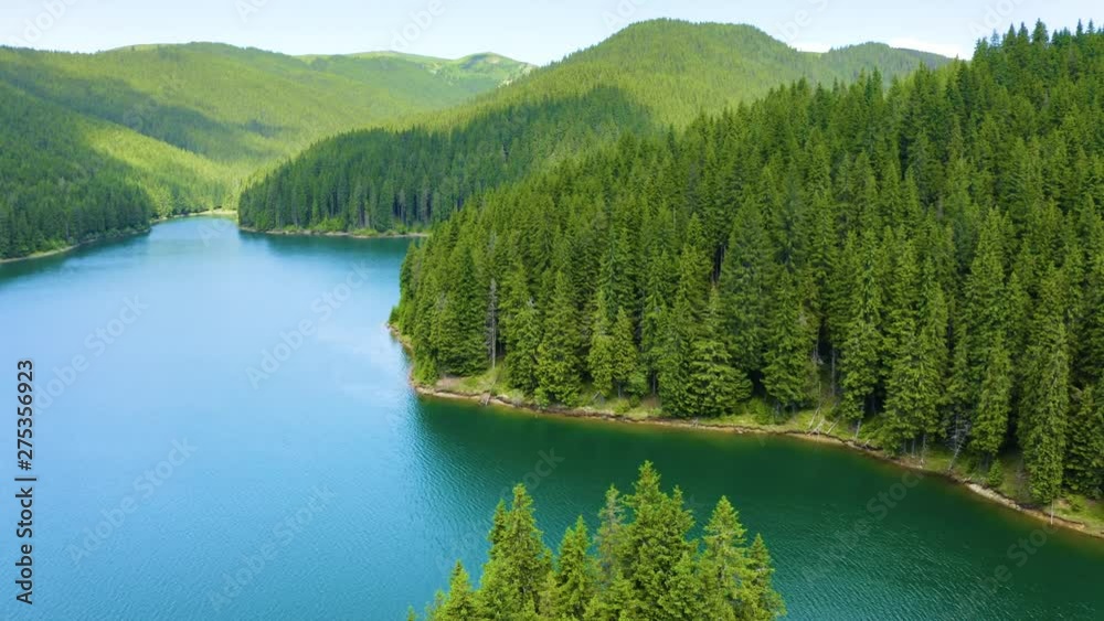 Mountain lake with turquoise water and green trees. Reflection in the water. Beautiful summer landscape with mountains, forest and lake. Aerial View. Drone shot over a beautiful mountain forest lake