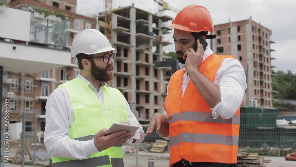 Engineer speaks on Mobile phone on construction site and checks the work of the worker. Builder talks on smartphone. Unfinished Project. Engineer speaks on Mobile phone on construction site and checks the work of the worker. Builder talks on smartphone. Unfinished Project.