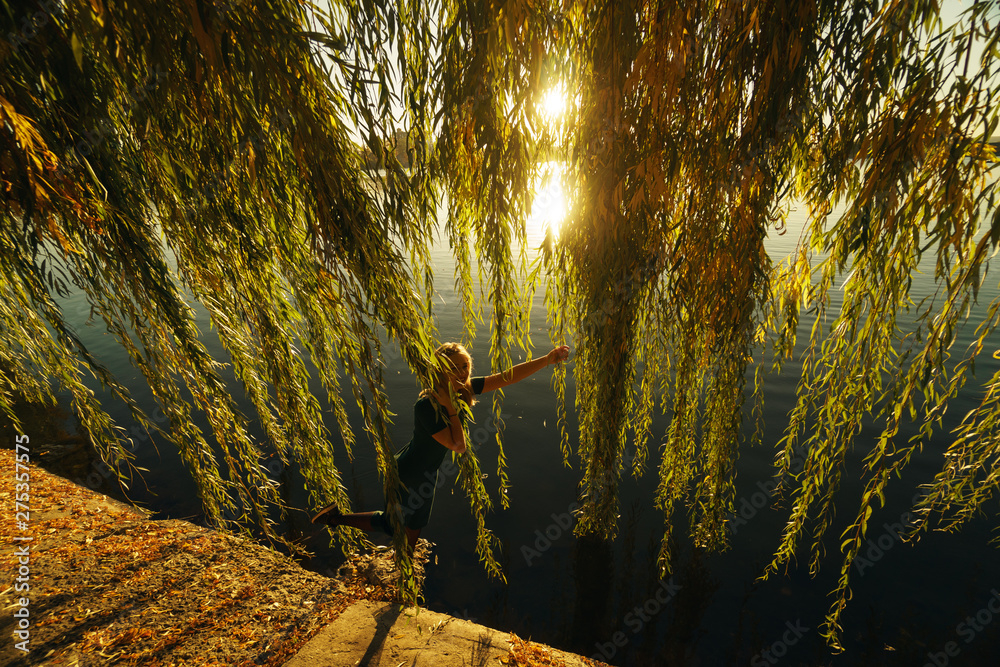 Φωτογραφία Autumn portrait of smiling young girl near willow on the background of a lake at