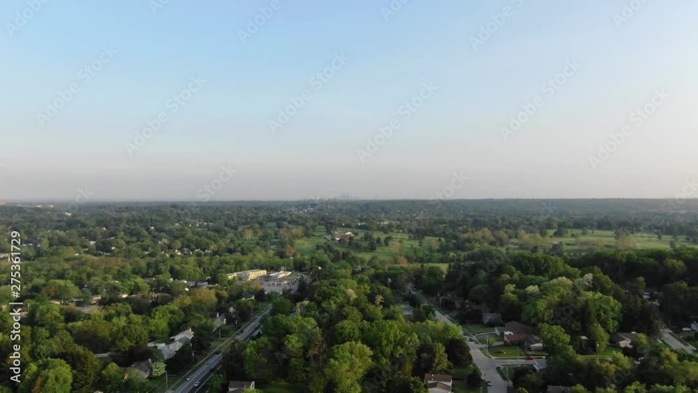 Green neighborhood flyover with skyline in distance Green neighborhood flyover with skyline in distance