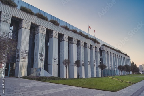 Palace of Justice, building housing the headquarters of various courts in Warsaw, columns of the building decorated with Latin legal sentences, in front of the building lawn and trees