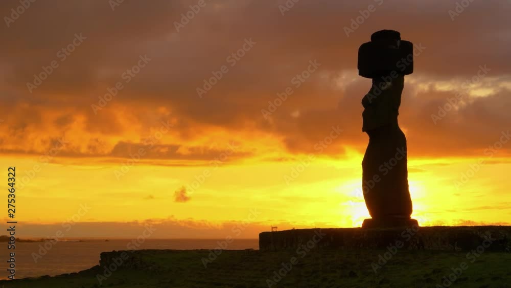AERIAL, SILHOUETTE, COPY SPACE, SUN FLARE: Stunning golden sunbeams shine on ancient moai in Ahu Tahai set right by the beach. Scenic shot of freight ships behind a famous sculpture on Easter Island AERIAL, SILHOUETTE, COPY SPACE, SUN FLARE: Stunning golden sunbeams shine on ancient moai in Ahu Tahai set right by the beach. Scenic shot of freight ships behind a famous sculpture on Easter Island