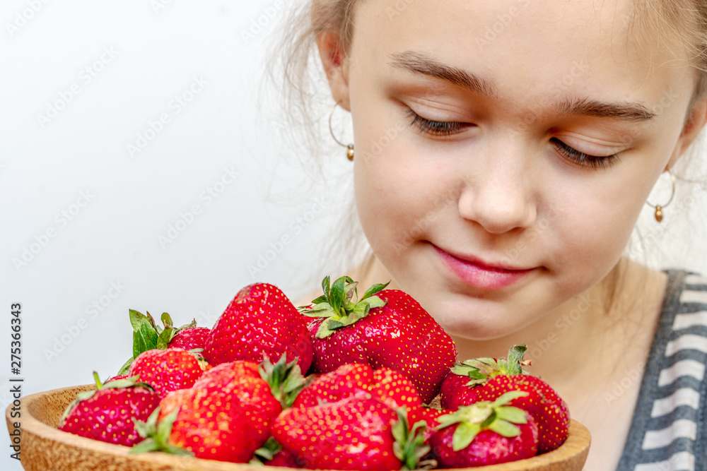 Wooden plate with strawberries in girl hand on light background, organic food concept Wooden plate with strawberries in girl hand on light background, organic food concept