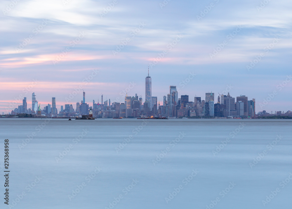 View on Financial District statue of liberty and jersey city from Hudson river at sunset with long exposure
