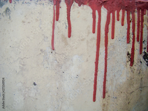 Drops of red paint flow on the old light wall.
