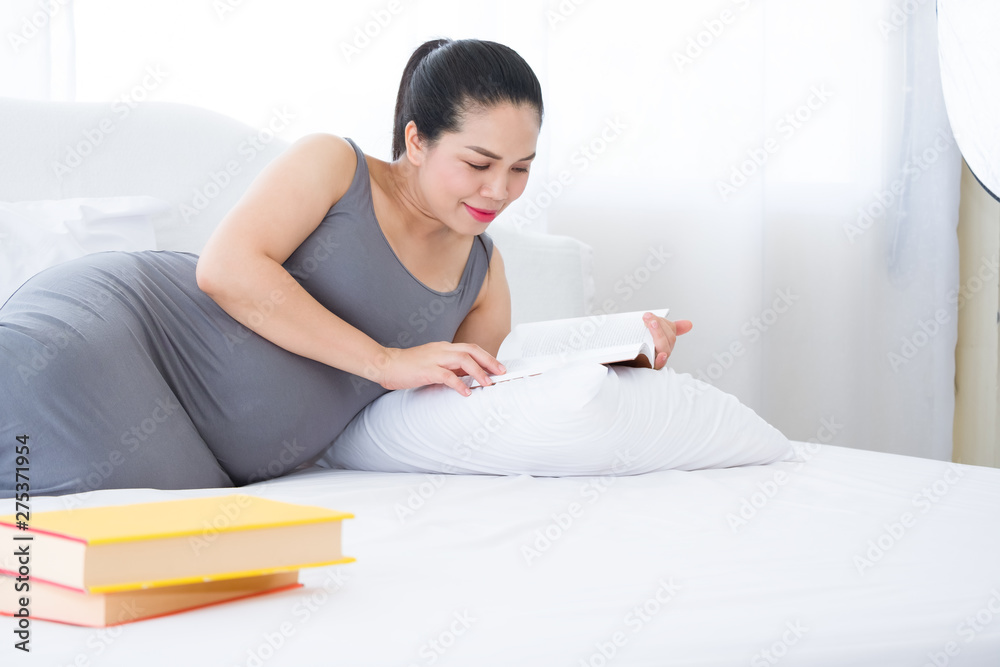 Pregnant woman reading a book on the white bed. Mental health care and pregnancy. Pregnant woman reading a book on the white bed. Mental health care and pregnancy.