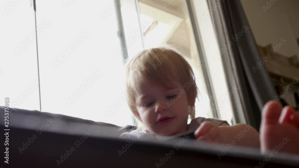 baby toddler girl sits on couch with smart phone baby toddler girl sits on couch with smart phone