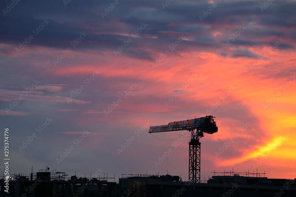 Naklejka premium Tower crane in construction site for urban development project during sunset for engineering design purpose with copy space