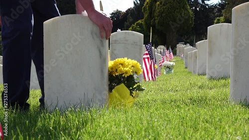 Man Putting Flowers by Military Headstone