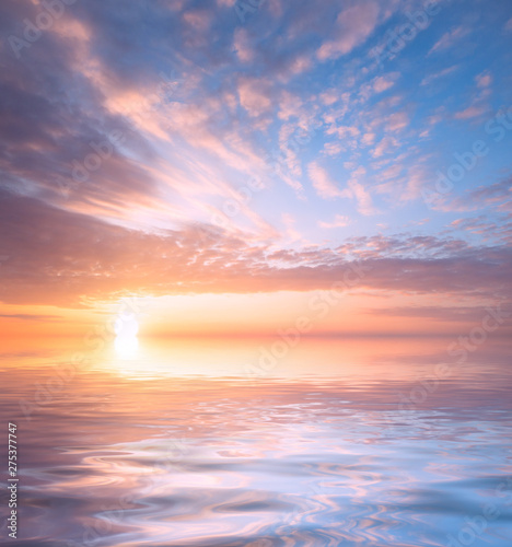 Beautiful sunset, bright sun and soft, multicolored clouds against the background of the sea.