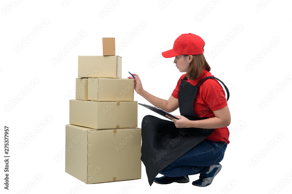 Delivery woman in red uniform with apron and Parcel boxes making notes on delivery receipt clipboard, isolated on white Delivery woman in red uniform with apron and Parcel boxes making notes on delivery receipt clipboard, isolated on white