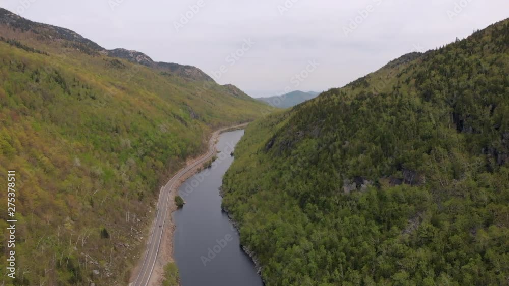 Aerial flight between lush Northeastern mountains, overlooking a still lake and two-lane highway. Aerial flight between lush Northeastern mountains, overlooking a still lake and two-lane highway.