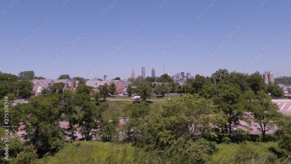 Cleveland, Ohio skyline as seen from the mounds in Tremont, a nearby neighborhood. The CLE big three building shine bright on a sunny day with blue skies. Cleveland, Ohio skyline as seen from the mounds in Tremont, a nearby neighborhood. The CLE big three building shine bright on a sunny day with blue skies.