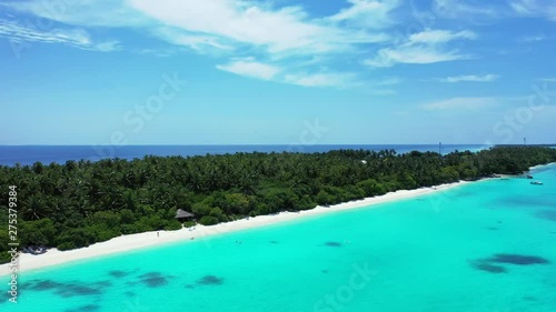 Drone approaching a white beach in a resort island in the Philippines, with a lush vegetation, few people on the beach and amazing azure waters photo