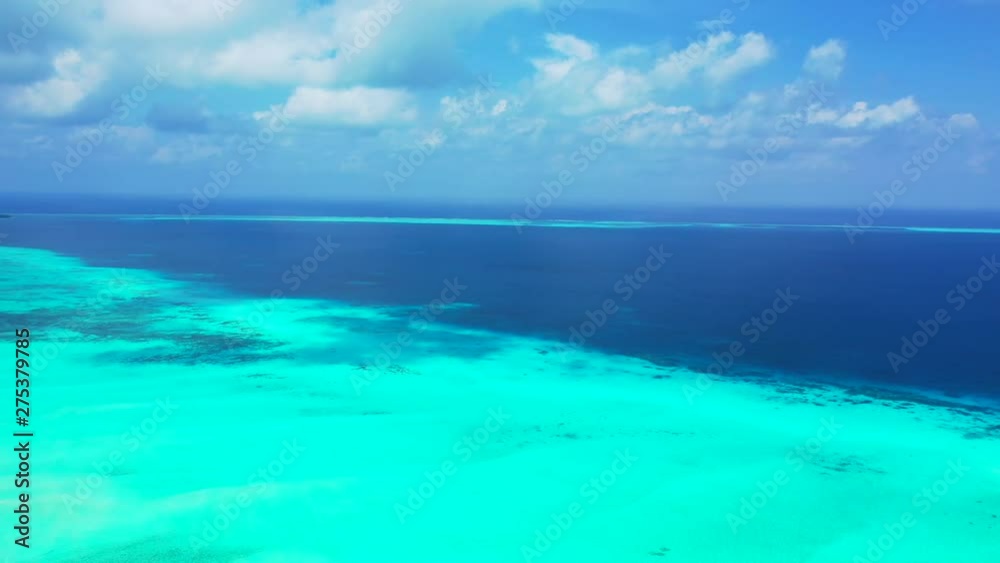 Drone flying over the border of the reef in the Maldives islands, with deep blue waters of the Indian Ocean extending beyond Drone flying over the border of the reef in the Maldives islands, with deep blue waters of the Indian Ocean extending beyond