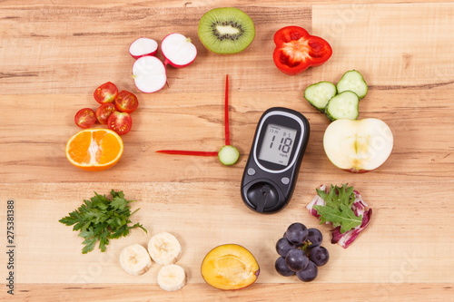 Glucometer with sugar level and fruits with vegetables in shape of clock, healthy breakfast for diabetics concept