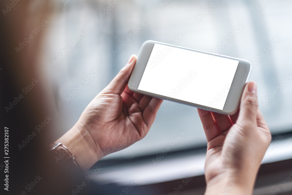 Mockup image of a woman holding white mobile phone with blank desktop screen in cafe Mockup image of a woman holding white mobile phone with blank desktop screen in cafe