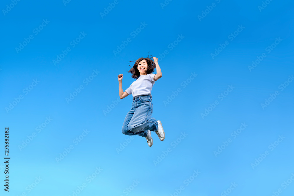 青空を背景にジャンプする女性。幸せ、飛躍、未来イメージ
