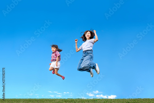 青空を背景に一緒にジャンプする親子。 絆、愛情、幸せ、飛躍、未来イメージ