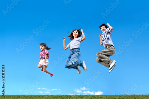 青空を背景に親子一緒にジャンプする家族。絆、愛情、幸せ、飛躍、未来イメージ