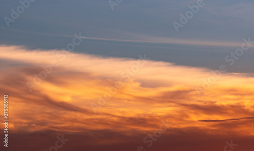 Beautiful blue and golden sky and clouds abstract background. Yellow-orange clouds on sunset sky. Warm weather background. Art picture of sky at sunset. Sunset and fluffy clouds for inspiration.