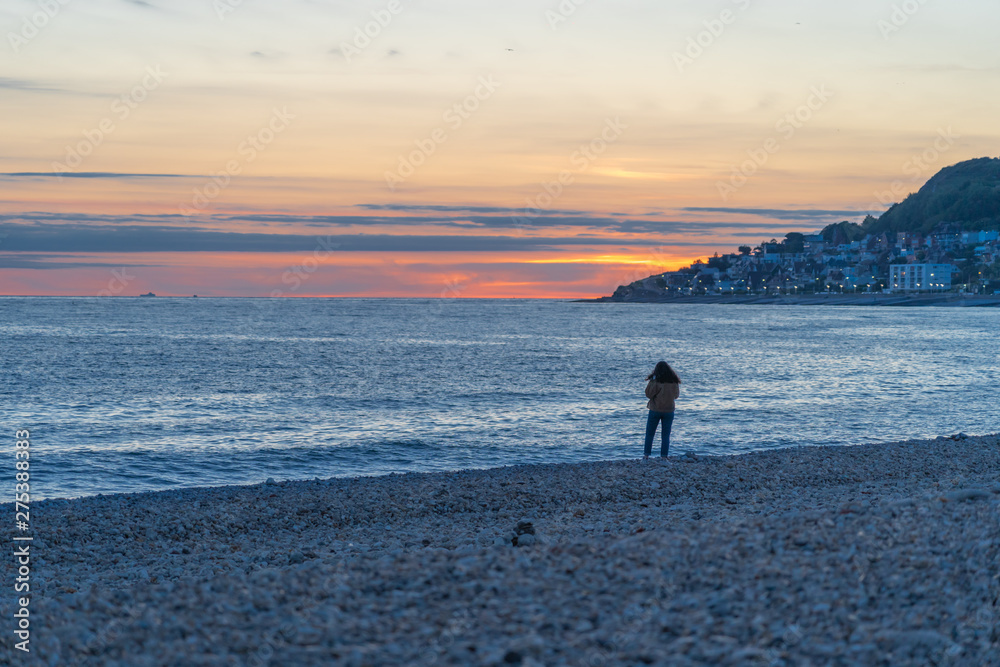 Le Havre, France - 05 30 2019: A woman standing on the beach at sunset