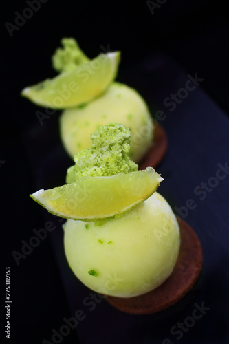 Green lime desserts on chocolate cookie with fresh lime slices and pistachio sponge