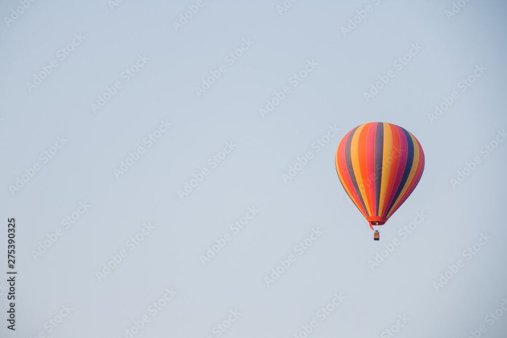 Naklejka premium Colorful hot air balloon moving up in blue sky.