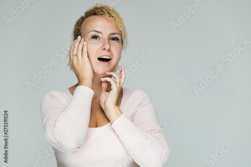 Photo portrait of a beautiful girl blonde woman with short curly hair on a white background talking and showing a lot of emotions. An experienced model shows hands. Beauty.