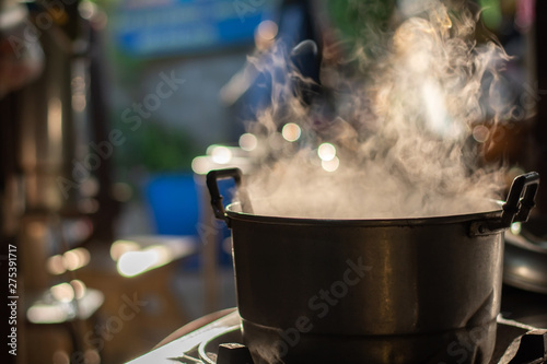 Metal pot boil soup on gas stove with smoke in Thai kitchen. Make food for breakfast.