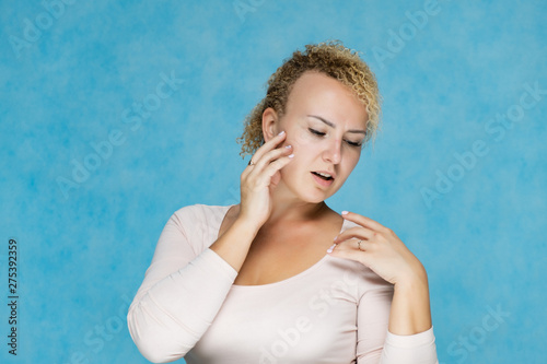 Photo portrait of a beautiful girl blonde woman with short curly hair on a blue background talking and showing a lot of emotions. An experienced model shows hands. Beauty. Made in studio