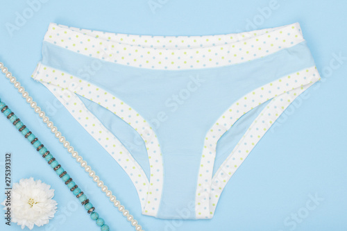 Beautiful women's panties with necklace and flower on blue background.