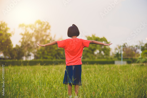 Kid standing and stretch the arms or extend arms in the grass fields