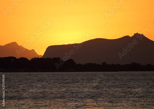 evocative image of the sunset over the sea with a promontory in the background in Sicily