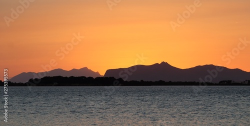 evocative image of the sunset over the sea with a promontory in the background in Sicily