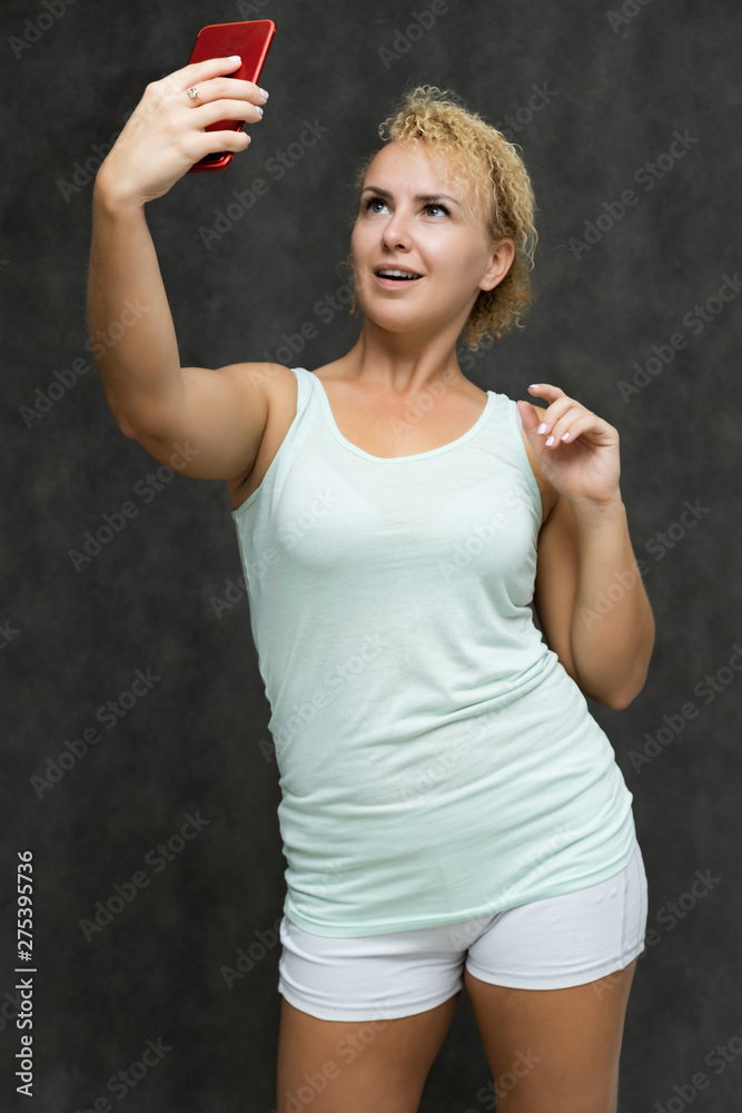 portrait above the knee of a beautiful blonde woman girl with short curly hair on a gray background in bright linen talking on the phone and showing a lot of emotions. Experienced model shows hands. portrait above the knee of a beautiful blonde woman girl with short curly hair on a gray background in bright linen talking on the phone and showing a lot of emotions. Experienced model shows hands.